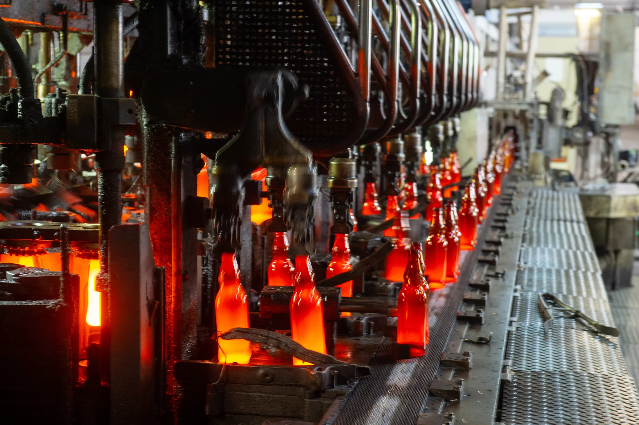 Glowing glass containers on an IS forming machine at the hot-end